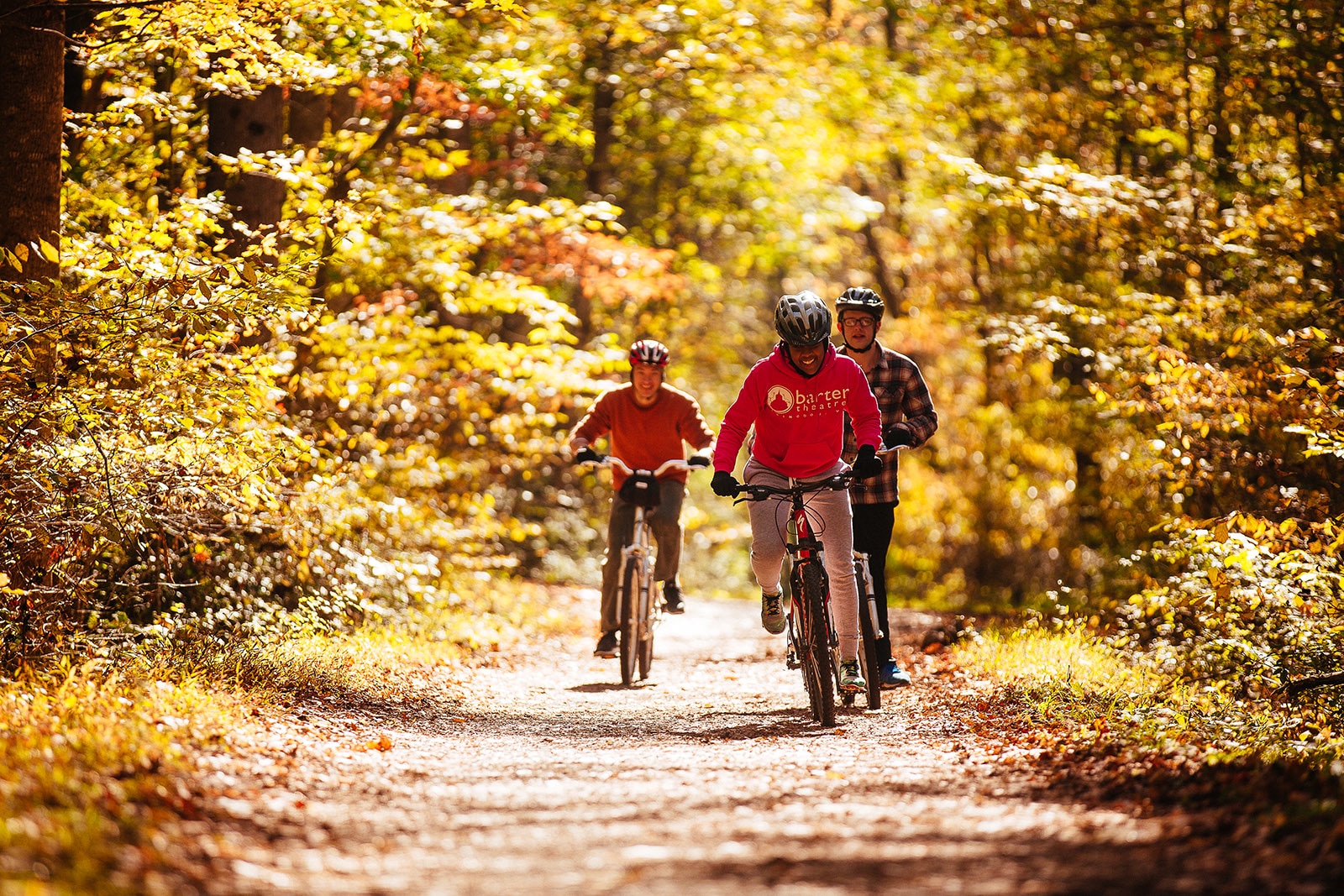 Three men riding bikes through fall scenery